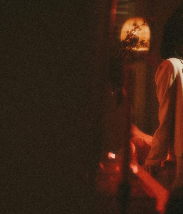 Woman performing a serene yoga pose in a dark, atmospheric setting with red light accents.